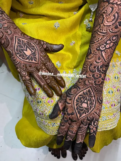 A close-up shot showcasing the fine details and shading within the 'AM' initial mehendi.