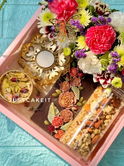 This Diwali gift hamper is designed to impress. It combines a dark chocolate artisanal bar with Kesar Rose fudge, a savory mix, a decorative diya, and a corner of fresh flowers.