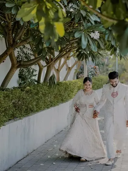 A happy, walking shot of the couple, capturing their movement and the flow of the bride's beautiful lehenga.