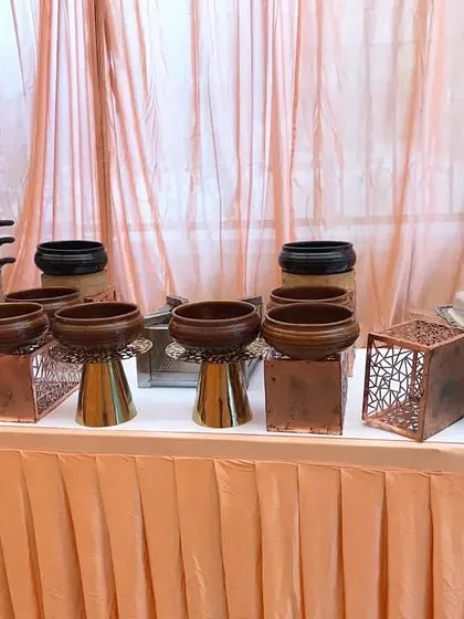 A display of our rustic-chic serveware, featuring wooden bowls on copper stands and a multi-tiered stainless steel steamer, perfect for a dim sum or momo station.