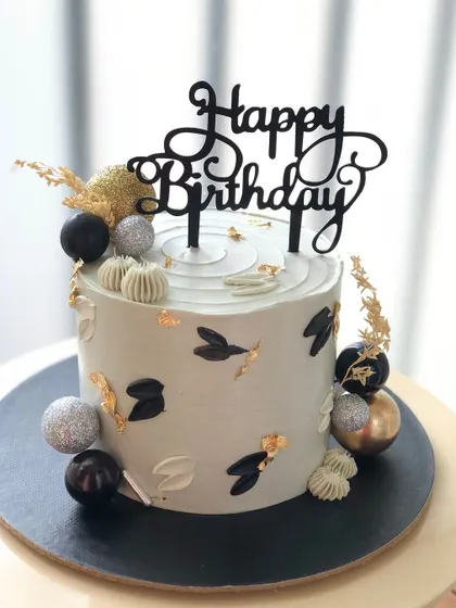 A sophisticated cake in muted tones with black, silver, and gold accents.