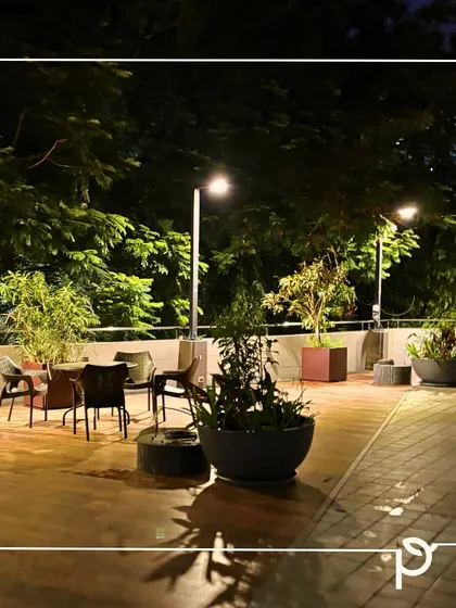 An evening view of a spacious terrace garden designed for outdoor living. Thoughtful lighting highlights the seating area and planters, transforming the space into a magical retreat after sunset.