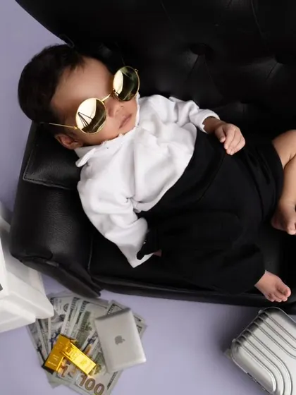 The boss baby is ready for business, complete with sunglasses and bags of money. This playful theme shows the fun side of newborn photography.