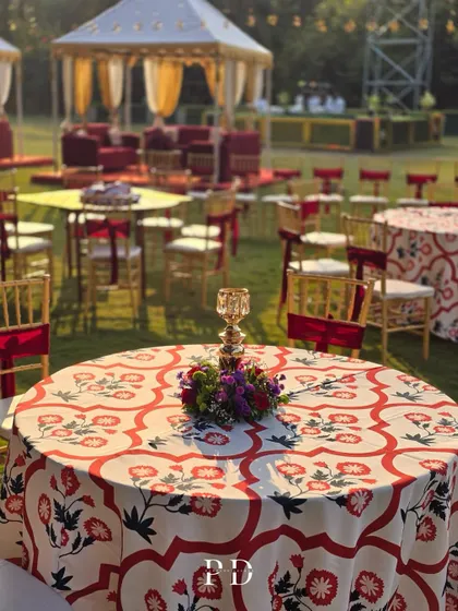 Custom-designed table linens with red and white floral patterns for a Sufi-themed Sangeet. This detail ties the entire decor together, from the large tents to the individual place settings.