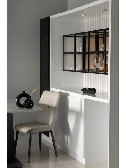 This detail shot highlights the custom bar and crockery unit. The design features a mix of open and closed storage, with a black metal grid shelf for displaying glassware, set against a white fluted backdrop.
