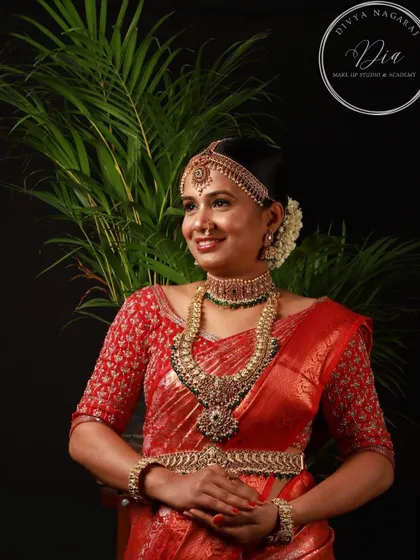 This professionally captured photo showcases a complete South Indian bridal look. The makeup is designed to be bold yet elegant, with defined eyes and a warm lip colour that enhances the bride's features. Paired with an elaborate hairstyle and antique jewellery, this is a classic look for any traditional wedding ceremony.