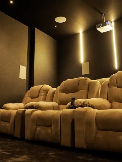 A compact 7.1.2 home cinema in Aruppukottai, featuring a simple, dark design with vertical LED lighting and comfortable fabric recliners.