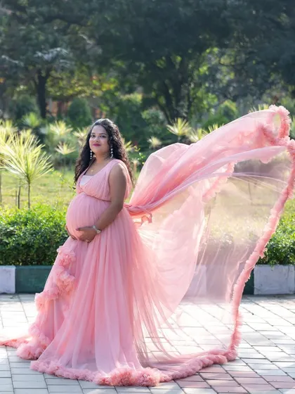 A dynamic outdoor shot of a mom-to-be in a pink gown with a beautiful flowing train.