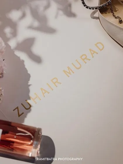 A flat-lay of the bride's luxurious details, including her Zuhair Murad shoes, perfume, and a bouquet of peonies.