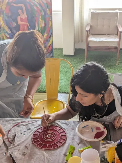 A participant working on a Lippan art piece, carefully arranging the mirrors and clay.