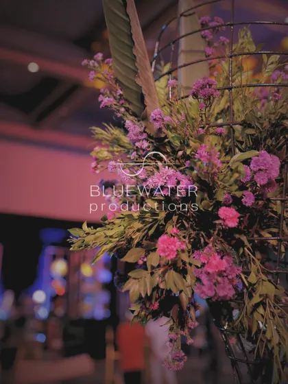 A close-up of a floral arrangement for a Sangeet, with purple and pink blooms in a modern wire-frame vase.