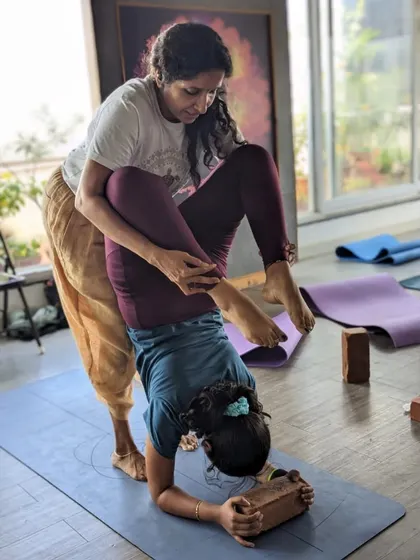 A teacher's touch can make all the difference. Here, a student receives guidance in a challenging inversion, showcasing the supportive and nurturing environment of our TTC.
