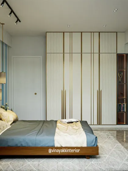 A full view of the bedroom, showcasing the floor-to-ceiling wardrobe with elegant vertical grooves and metallic handles. The design provides massive storage while maintaining a light and airy feel.