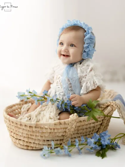 A profile shot of this lovely baby girl, capturing her happy smile and the delicate details of her lace bonnet.