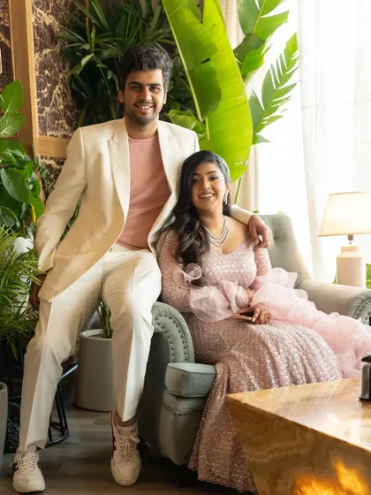 A relaxed portrait of the couple seated in a chic, plant-filled setting during their engagement party.
