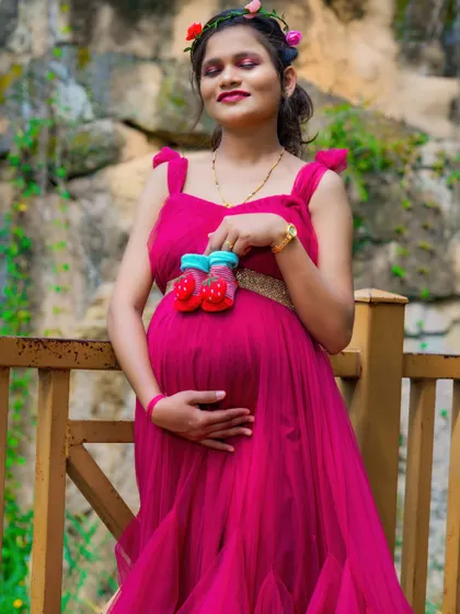 A sweet solo portrait where the mom-to-be holds a pair of tiny red shoes over her bump. This is a colorful and symbolic way to include the baby in the photos.