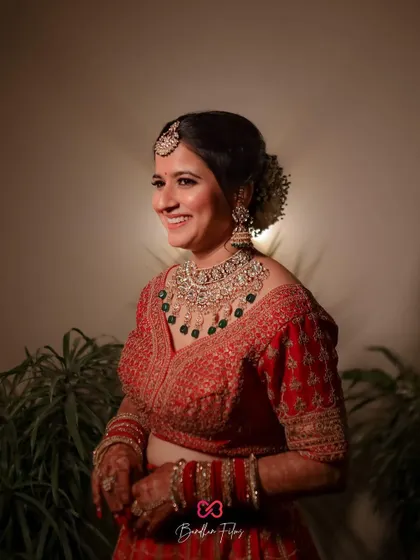 A smiling portrait of the bride in her red wedding lehenga, looking radiant and happy.