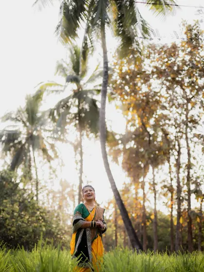 A low-angle shot of the bride standing in a field with tall palm trees behind her, creating a majestic and beautiful portrait.