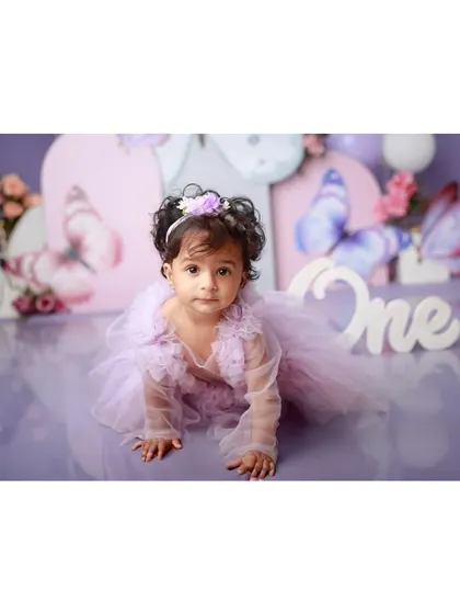 A sweet baby girl crawling in a butterfly-themed first birthday setup.