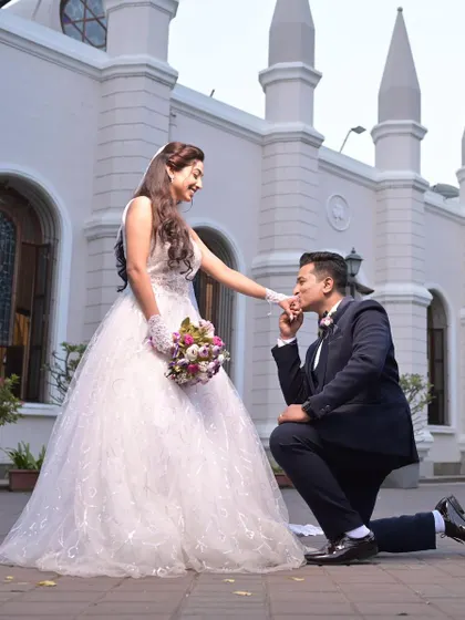 A fairytale proposal. The groom gets on one knee for his bride, who looks absolutely stunning in a classic white ball gown, perfect for a church ceremony.
