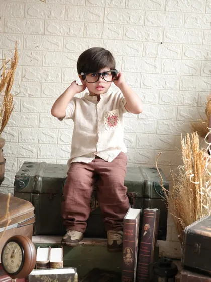 Adjusting his glasses, this little boy looks thoughtful in our vintage explorer setup. The earthy tones and retro props create a warm and nostalgic atmosphere.