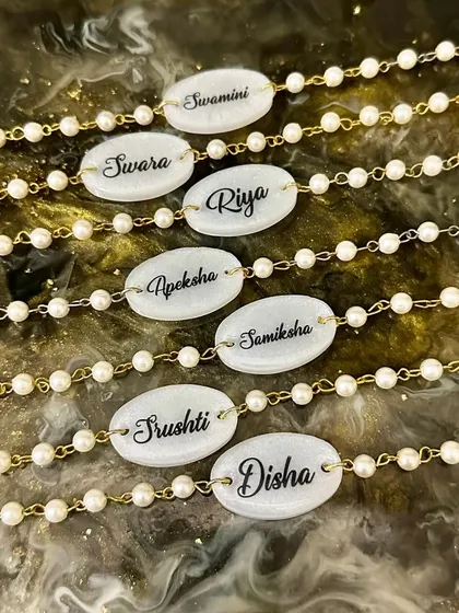 For Raksha Bandhan, I create these beautiful unisex rakhi bracelets with personalized nameplates set in resin, surrounded by pearl and gold-colored beads.