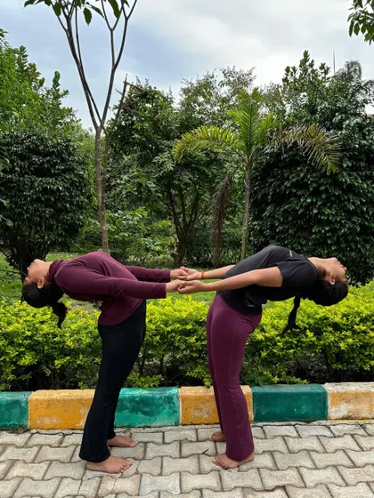 A partner backbend, holding hands for support. This pose helps build trust and allows for a deeper stretch than one could achieve alone.