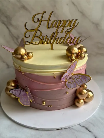 A whimsical butterfly-themed cake with a beautiful purple ombre effect. The design is adorned with delicate wafer paper butterflies and clusters of gold spheres.