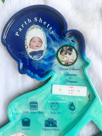 The top portion of the motherhood frame, featuring the baby's name, photos, and the preserved pregnancy test. The deep blue and turquoise resin creates a beautiful ocean wave effect.
