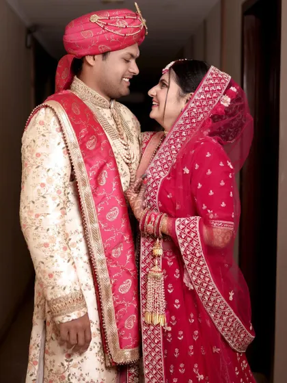 The couple shares a look of love and admiration in this classic wedding portrait. The image captures the elegance of their attire and the happiness of the moment.