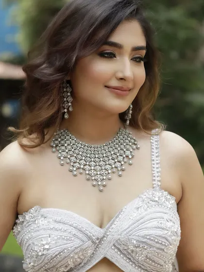 A soft, smiling portrait of the 'Sitara' look. The makeup enhances her features, creating a radiant and confident glow perfect for a sangeet or reception.