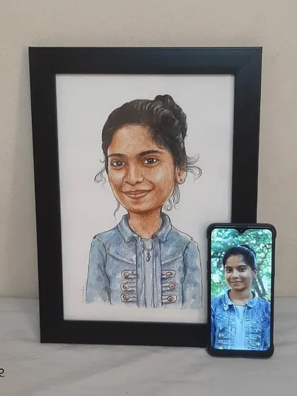 The final handmade caricature, framed and placed next to the original photo for comparison.