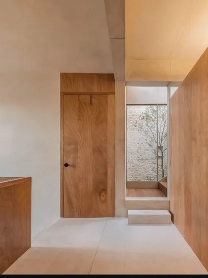 Minimalist design often involves connecting with the outdoors. This space features a simple wooden door and a transition to a small internal courtyard, bringing natural light and a sense of openness into the home.