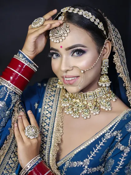 A stunning bridal look in a royal blue lehenga, featuring heavy kundan jewelry and dramatic eye makeup.