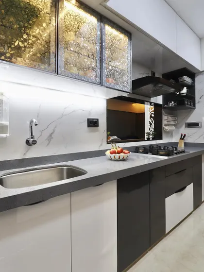 A close-up of the kitchen sink and cabinet area. This view highlights the patterned glass on the overhead cabinets and the sleek, handleless design of the lower drawers, contributing to a clean, modern aesthetic.