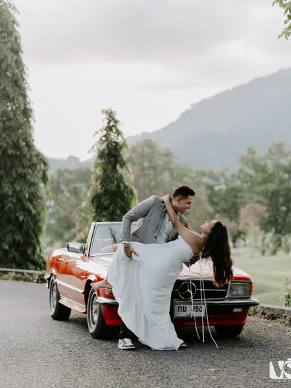 A classic romance scene with a vintage red Mercedes. This shot captures a timeless, movie-like dip against the beautiful hills of Thailand, showing our love for creating iconic, romantic pre-wedding photographs.