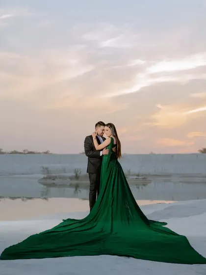 A full-length shot showcasing the couple and the stunning green trail gown against the vast, white landscape. This is the kind of "wow" shot that belongs on a large canvas.