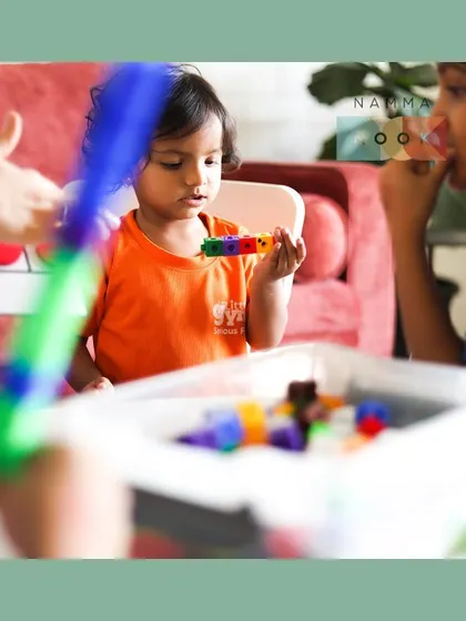 A young child at a Namma Nook workshop intently examining a tower of connecting cubes. This focused play is where deep learning happens.