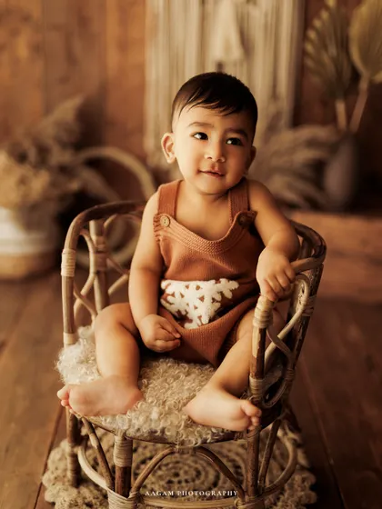 A sweet, gentle smile from a baby boy during his boho-themed sitter session. The natural props and warm lighting create a beautiful, serene image.