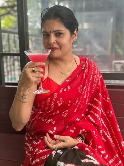 Enjoying a cocktail in my custom red and black Bandhani saree. My designs are made to be lived in, whether you're at a formal event or a casual brunch.