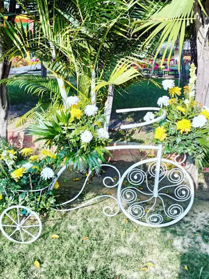 A decorative white bicycle filled with flowers, a whimsical and charming photo prop for a daytime wedding event.