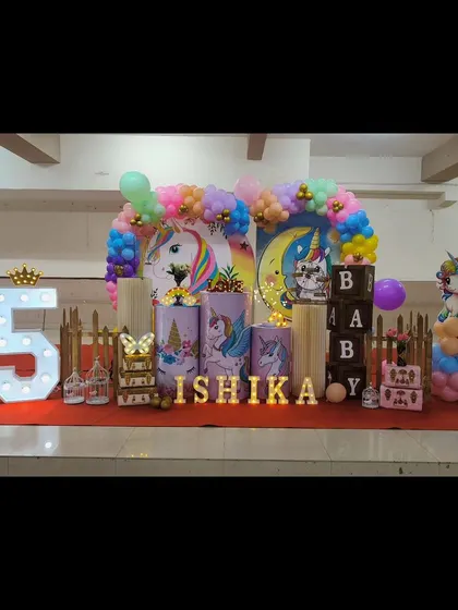 Our unicorn theme is pure magic. This setup for Ishika's birthday features pastel unicorn illustrations on pedestals, a rainbow balloon arch, and light-up letters for an enchanting party.