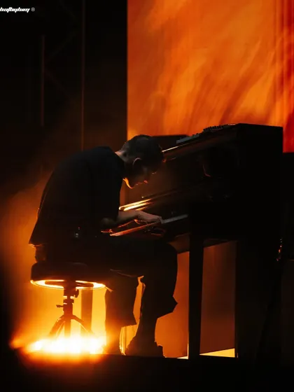 Ben Böhmer in a moment of quiet intensity, focused on his keyboard during his live set in Bangalore. The warm, focused lighting creates an intimate portrait amidst the large-scale production, showing a different side of live performance.