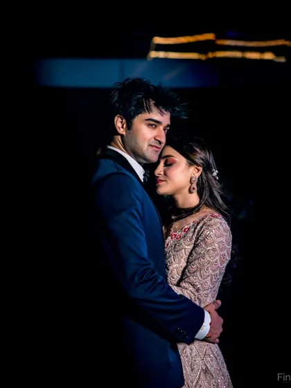 A dramatic, low-light portrait from a Sangeet night. The dark background makes the couple the sole focus, emphasizing their intimate embrace.