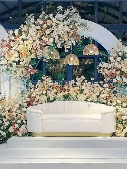 A closer view of the glasshouse reception stage, showing the intricate floral work and hanging wicker lamps.