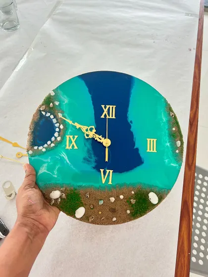 A beach resin clock in progress, showing the placement of the clock hands.
