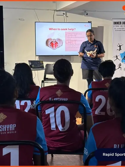 An over-the-shoulder view of elite football players listening to a presentation on when to seek medical help for menstrual issues. We empower athletes to recognize symptoms and advocate for their own health.