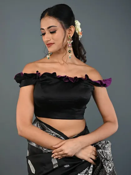 An elegant off-the-shoulder blouse in black satin with a delicate purple ruffle. This design is perfect for evening events and cocktail parties.