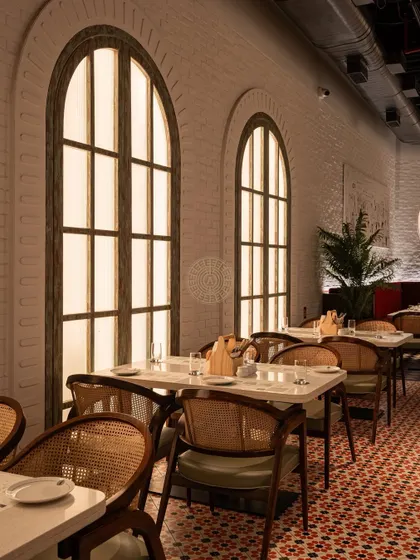 The arched windows are a recurring motif, adding a sense of classical elegance and softness to the restaurant's design.