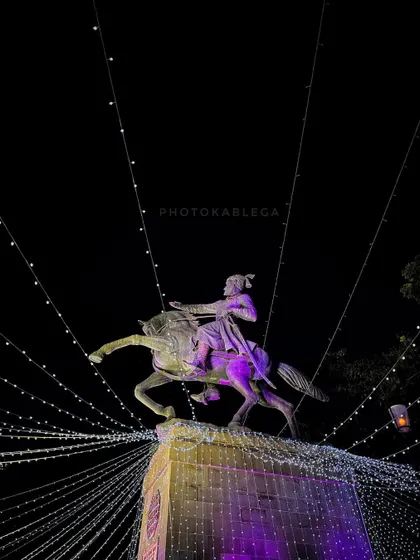 The Shivaji Park statue decorated with festive lights at night, creating a beautiful display of light trails.